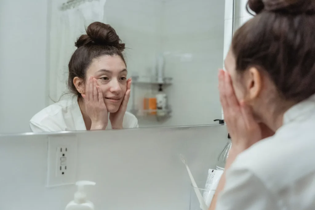 Woman examining common skin concerns including acne, redness, and dry skin