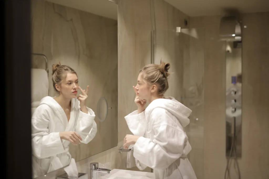 Woman following a beginner skincare routine using cleanser, moisturizer, and sunscreen.