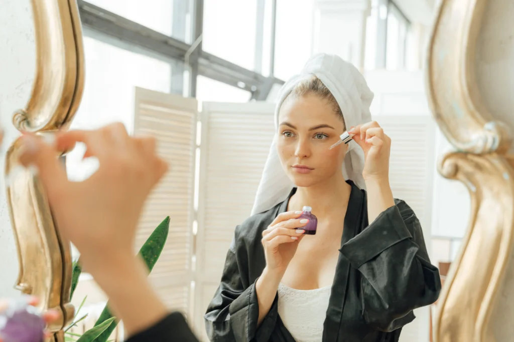 Woman following a daily skincare routine using cleanser, serum, moisturizer, and sunscreen for healthy-looking skin.