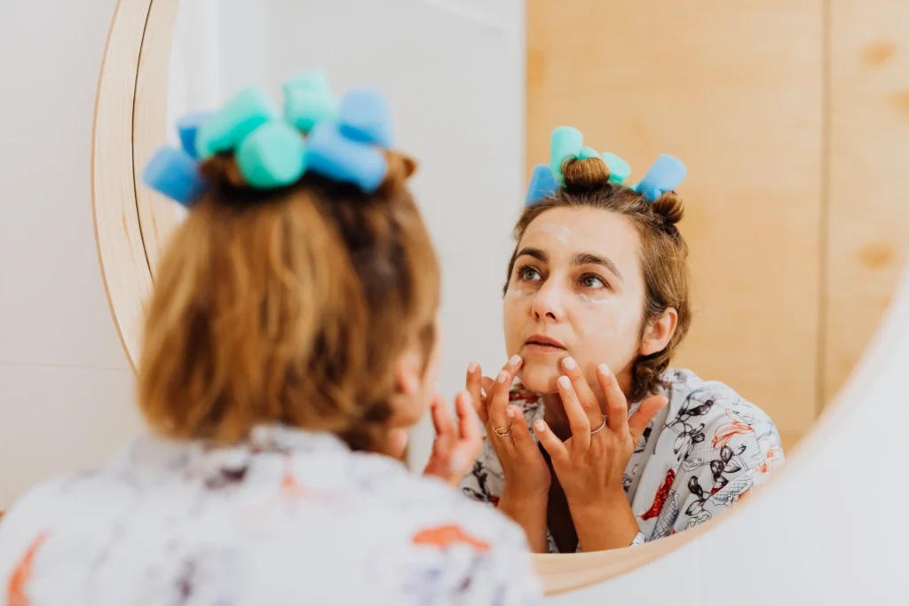 Woman following a beginner skincare routine using cleanser, moisturizer, and sunscreen.