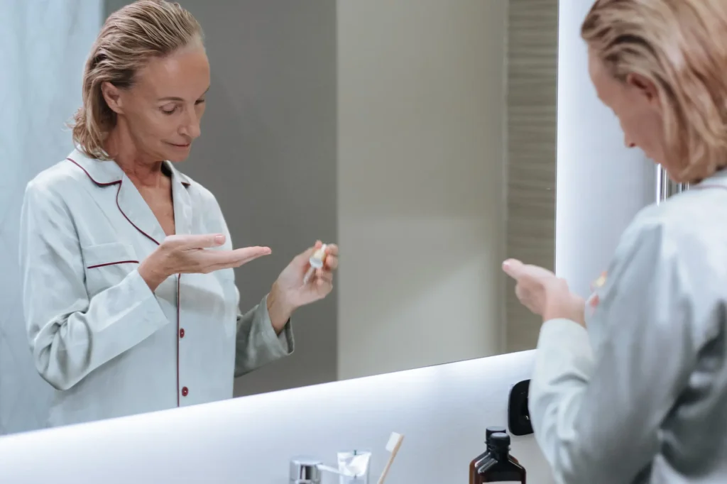 Woman following a daily skincare routine using cleanser, serum, moisturizer, and sunscreen for healthy-looking skin.