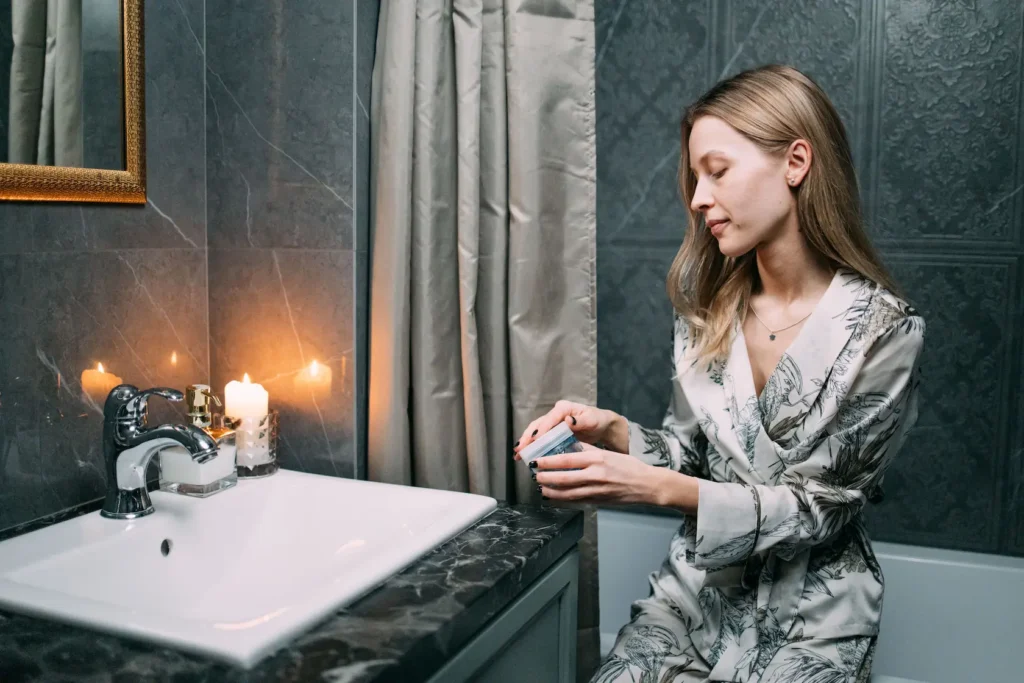Woman following a beginner skincare routine using cleanser, moisturizer, and sunscreen.