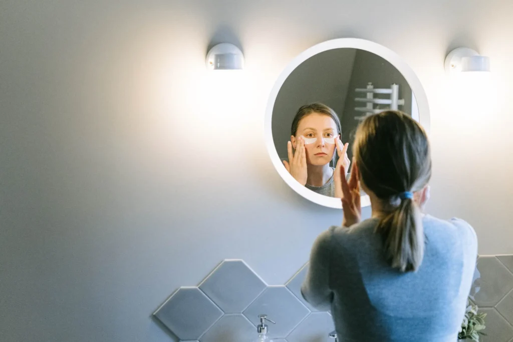 Woman following a beginner skincare routine using cleanser, moisturizer, and sunscreen.